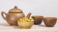 ceramic brown teapot with cups and a wooden bowl with cookies on a white table background