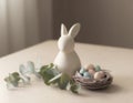 Ceramic bunny with pastel eggs and eucalyptus on softly lit tabletop Royalty Free Stock Photo
