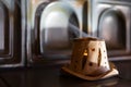 A ceramic candlestick with a smoky trail from a candle stands on a tiled fireplace