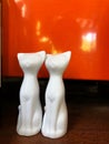Ceramic cats on wooden table with orange background.