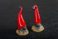 Ceramic Christmas elves in red hats on a black background Royalty Free Stock Photo