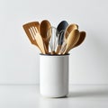 A ceramic container holds a selection of wooden and metal kitchen utensils. The Royalty Free Stock Photo