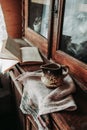 Ceramic Cup with a spout and handle on a waffle towel on an old retro wooden closet with glass doors and natural light from the