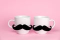Ceramic cups decorated with black moustache. Cute romantic card for gay couple on  Valentine`s day on a pink background Royalty Free Stock Photo