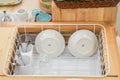 Ceramic dish and stainless cutlery set in plastic drainer after washing