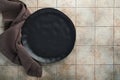 Ceramic empty black plate and linen kitchen towel napkin on old ceramic tile table background. Cooking stone backdrop. Top view Royalty Free Stock Photo