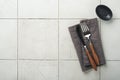 Ceramic empty black plate, silverware and linen kitchen towel napkin on old ceramic tile table background. Cooking stone backdrop Royalty Free Stock Photo