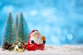 Ceramic figure of Santa Claus, fir cones and balls in the snow among the Christmas trees on an abstra