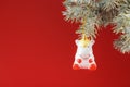 Ceramic Figure of a Unicorn on a spruce branch, on a red background. Free space for text