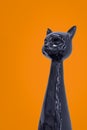 Ceramic figurine of black elegant cat on orange background. Royalty Free Stock Photo