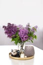 Ceramic figurine of rabbit bunny next to bouquet of lilac flowers in vase and candlestick on an table, on an isolated white backgr Royalty Free Stock Photo