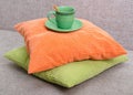 Ceramic green cup with a saucer and an orange teaspoon on a pile