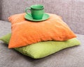 Ceramic green cup with a saucer on a pile from green and orange