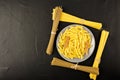 Ceramic grey plate with dry pasta and chicken and spaghetti on a soft-blurred textured black background Royalty Free Stock Photo