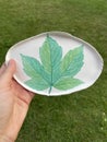 Ceramic handmade plate with a green maple leaf