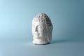 Ceramic head of a Buddha on a blue background. Minimal concept, copy space Royalty Free Stock Photo