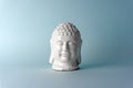 Ceramic head of a Buddha on a blue background. Minimal concept, copy space Royalty Free Stock Photo