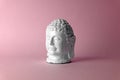 Ceramic head of a Buddha on a pink background. Minimal concept, copy space Royalty Free Stock Photo