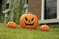 Ceramic Jack O`Lanterns on front lawn of house. Traditional Halloween decor