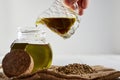 Ceramic jar pouring virgin vegetable oil in a glass bottle and hemp seeds on sackcloth. close up Royalty Free Stock Photo