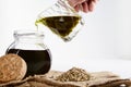 Ceramic jar pouring virgin vegetable oil in a glass bottle and hemp seeds on sackcloth. close up Royalty Free Stock Photo