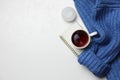 Ceramic mug with aromatic tea, blue knitted sweater, notebook and candle on white background, flat lay. Space for text