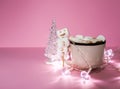 Ceramic mug with hot fresh cocoa drink and handmade funny marshmallow snowman on soft pink background Royalty Free Stock Photo