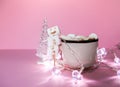 Ceramic mug with hot fresh cocoa drink and handmade funny marshmallow snowman on soft pink background Royalty Free Stock Photo