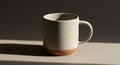 Ceramic mug with a speckled white glaze and terracotta base on beige surface Royalty Free Stock Photo