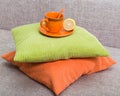 Ceramic orange cup with a lemon half on a saucer on a pile from