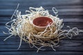 Ceramic piala in straw nest on black wooden desk