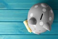 Ceramic piggy bank and banknotes on turquoise wooden table, top view. Space for text Royalty Free Stock Photo