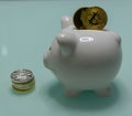 Ceramic Piggy bank with inserted bitcoin and ethereum and pile of coins besid closeup