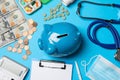 Ceramic piggy bank, stethoscope, money and pills on light blue background, flat lay. Medical insurance Royalty Free Stock Photo