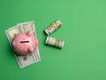 Ceramic pink piggy bank and paper american us dollars on green background Royalty Free Stock Photo