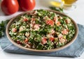 Ceramic plate of Arabic salad Tabbouleh on a white background with gray textiles