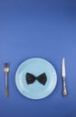 Ceramic plate with a cutlery and gift box on the blue paper background Royalty Free Stock Photo