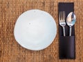 Ceramic plate. Empty white freeform shaped porcelain dish with spoon and fork in leather case on mat Royalty Free Stock Photo