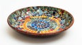 A ceramic plate with a mosaiclike design made up of small layered tiles in various colors and shapes.