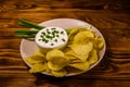 Ceramic plate with potato chips and glass bowl with sour cream on wooden table Royalty Free Stock Photo
