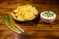 Ceramic plate with potato chips and glass bowl with sour cream on wooden table Royalty Free Stock Photo