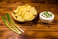 Ceramic plate with potato chips and glass bowl with sour cream on wooden table Royalty Free Stock Photo