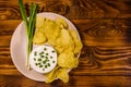 Ceramic plate with potato chips and glass bowl with sour cream on wooden table. Top view Royalty Free Stock Photo