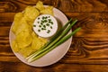 Ceramic plate with potato chips and glass bowl with sour cream on wooden table. Top view Royalty Free Stock Photo