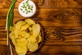 Ceramic plate with potato chips and glass bowl with sour cream on wooden table. Top view Royalty Free Stock Photo