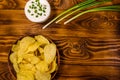 Ceramic plate with potato chips and glass bowl with sour cream on wooden table. Top view Royalty Free Stock Photo