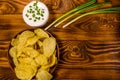 Ceramic plate with potato chips and glass bowl with sour cream on wooden table. Top view Royalty Free Stock Photo