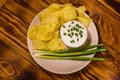 Ceramic plate with potato chips and glass bowl with sour cream on wooden table. Top view Royalty Free Stock Photo