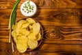 Ceramic plate with potato chips and glass bowl with sour cream on wooden table. Top view Royalty Free Stock Photo