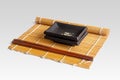 Ceramic plates, chopsticks and a bamboo mat on a light background